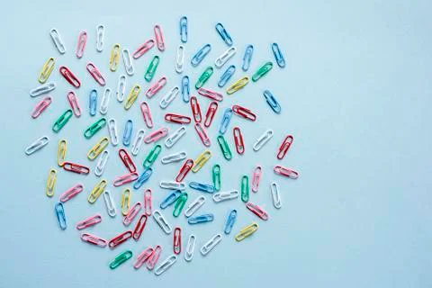 Multi-colored paper clips on blue background Stock Photos