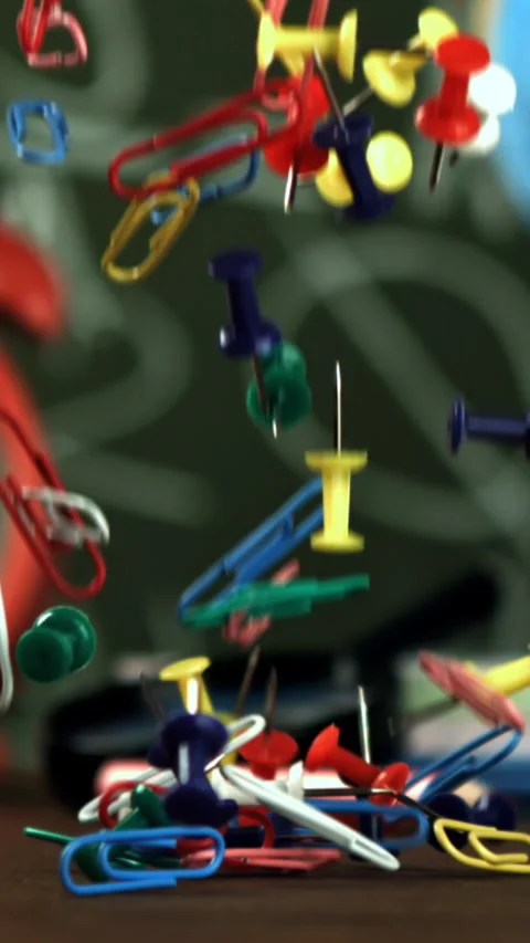 Multi-colored paper clips fall on the school desk. Filmed on a high-speed camera Stock Footage 335375110