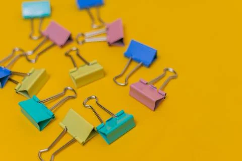 Multi-colored paper clips on a yellow background Stock Photos