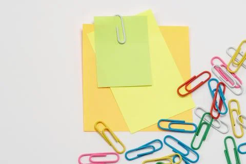 Multi-colored paper notes fastened with a paper clip on a white background. Stock Photos