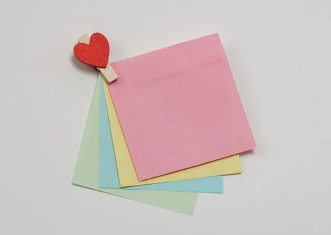 Multi-colored paper notes fastened with a wooden clothespin in heart form on  Fotos de archivo