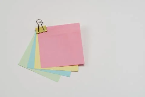 Multi-colored paper notes fastened with a paper binder clip on a white backgr Stockfoto's