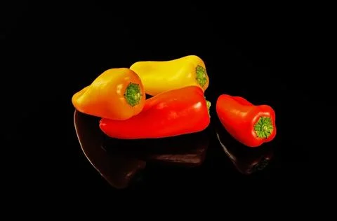 Multi-colored paprika is reflected in a black mirror table Stock Photos