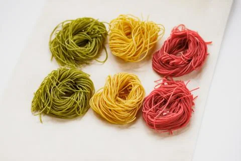 Multi-colored pasta nests, on baking paper, red, yellow and green colors Stock Photos