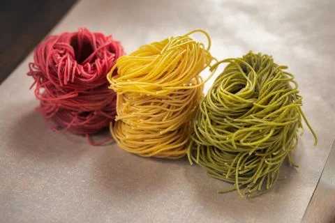 Multi-colored pasta nests, on baking paper, red, yellow and green colors Stock Photos