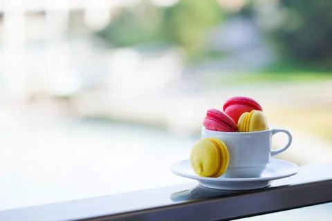 Multi-colored pastry macaroon in a white mug on a background of nature Foto stock