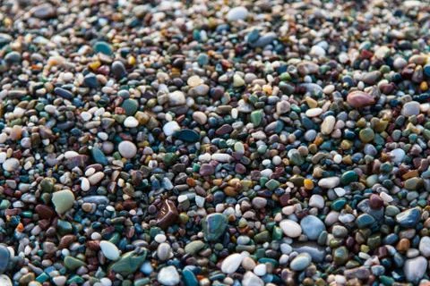 Multi-colored pebbles on the beach, washed by waves Stock Photos