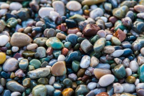 Multi-colored pebbles on the beach, washed by waves Stock Photos