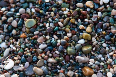 Multi-colored pebbles on the beach, washed by waves Stock Photos