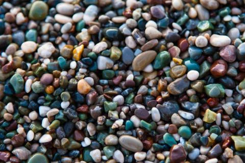 Multi-colored pebbles on the beach, washed by waves Stock Photos