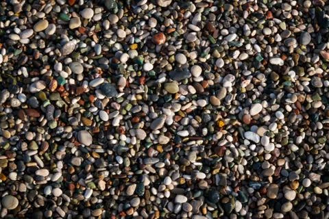 Multi-colored pebbles on the beach, washed by waves Stock Photos