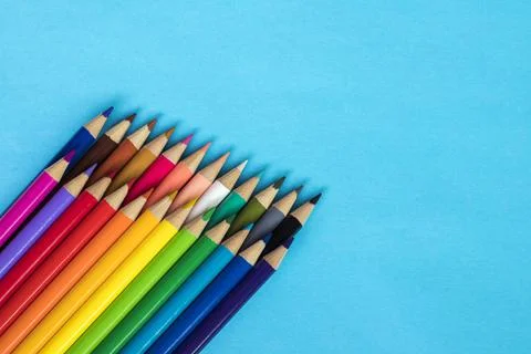Multi colored pencils on blue paper background Stock Photos