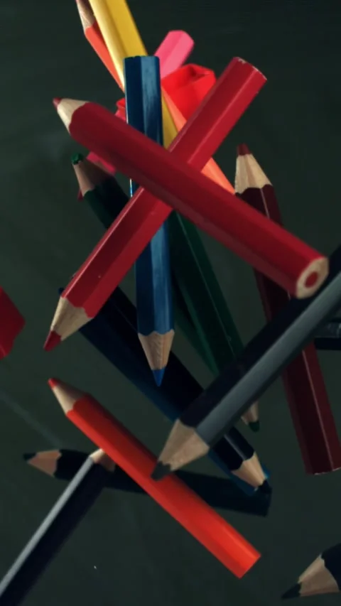 Multi-colored pencils flying against the background of a blackboard. Filmed on a Stock Footage 335372610