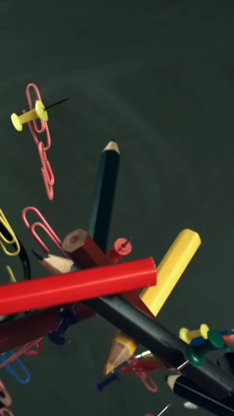 Multi-colored pencils flying against the background of a blackboard. Filmed on a Stock Footage 335377521