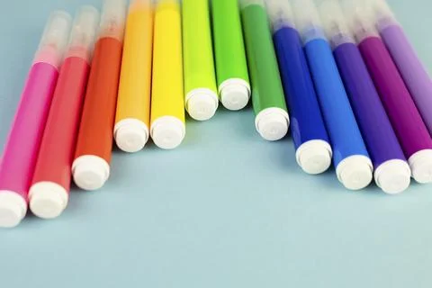 Multi-colored pencils in a glass cup on a white table. Stock Photos