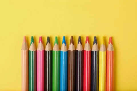 Multi-colored pencils on a yellow background with a place for text. Stock Photos