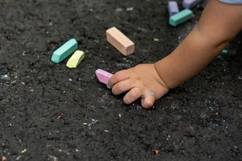 Multi-colored pieces of chalk lie on the black asphalt. Stock Photos