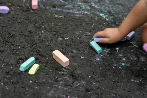 Multi-colored pieces of chalk lie on the black asphalt. drawing concept. Stock Photos