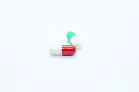 Multi-colored pill capsules are located on a white background Foto stock