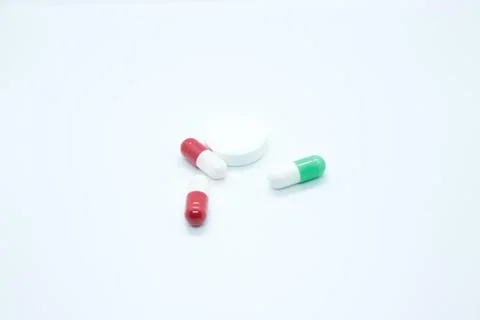 Multi-colored pill capsules are located on a white background Stock Photos