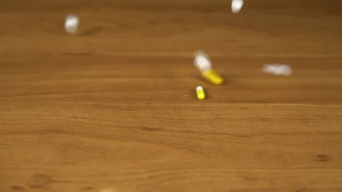 Multi-colored pills and capsules fall on the table Stock Footage 117132398
