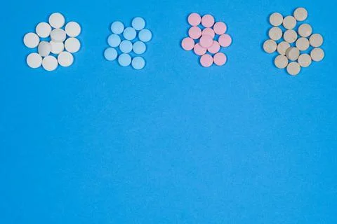 Multi-colored pills lie in heaps on a blue background. Copy space Stock Photos