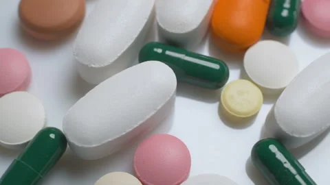 Multi-colored pills rotate on a white background Stock Footage 98033874