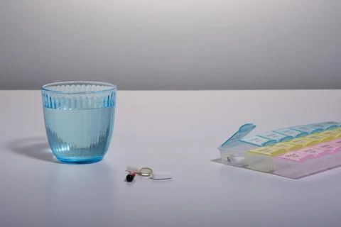 Multi-colored pills (vitamins) of different shapes lie on the table next to a Fotos Stock