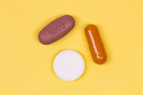 Multi-colored pills on a yellow background. Colorful medicines Stock Photos
