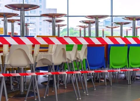 Multi-colored plastic chairs and tables in cafe closed by a protective tape. Stock Photos