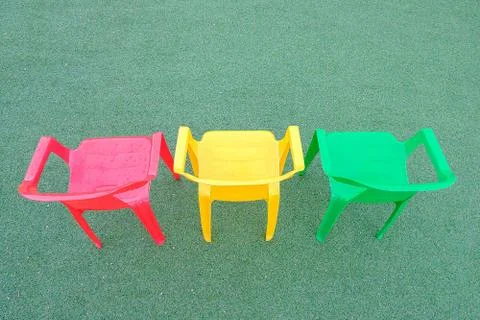 Multi-colored plastic chairs on a green background Stock Photos