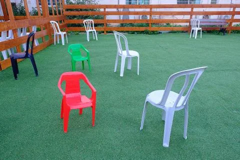 Multi-colored plastic chairs on a green background Stock Photos