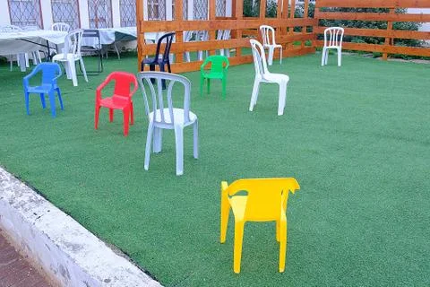 Multi-colored plastic chairs on a green background Stock Photos