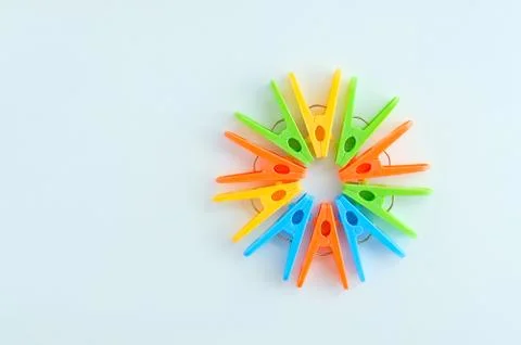 Multi-colored plastic clothespins lined in the shape of a circle. White backg Stock Photos