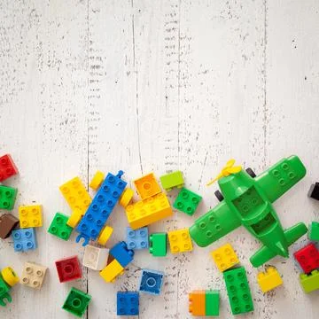 Multi-colored plastic cubes are scattered on a white wooden table. Top view Stock Photos