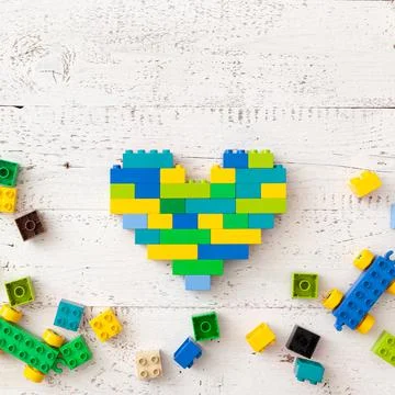 Multi-colored plastic cubes are scattered on a white wooden table. Top view Stock Photos