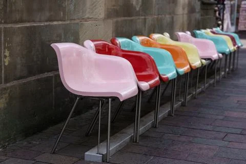 ..Multi-colored plastic seats in a row against a gray wall. Stock Photos