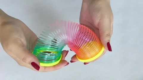 Multi-colored plastic spiral in womans hand on white background. Toys Stock Footage 318133578