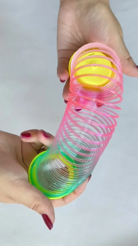 Multi-colored plastic spiral in womans hand on white background. Toys Stock Footage 318133591