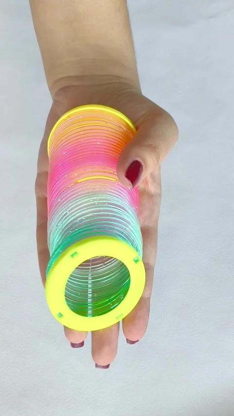 Multi-colored plastic spiral in womans hand on white background. Toys Stock Footage 318133697