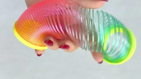 Multi-colored plastic spiral in womans hand on white background. Toys Stock Footage 318133748