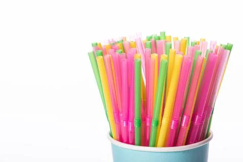 Multi colored plastic straws in disposable paper cup isolated on white backdrop Stock-Fotos
