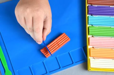 Multi-colored plasticine. Blue modeling board. Gray background. Stock Photos