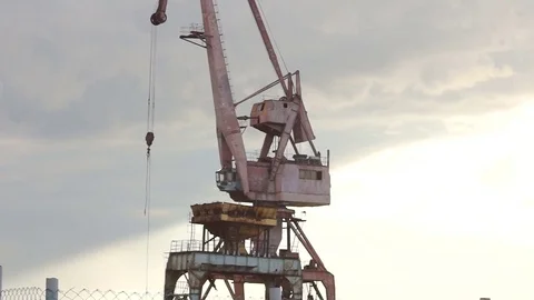 Multi-colored port gantry in background of sun peeping out from behind cloud Stock Footage 77576001