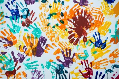 Multi-colored prints of hands smeared with paint on a white wall Stock Photos