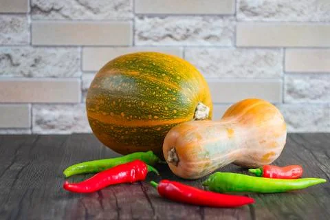 Multi-colored pumpkins and chili pepper  on  brown wooden table. Organic food Stock Photos