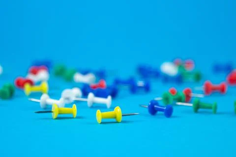 Multi-colored push pins on a blue background. Stock Photos