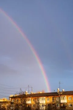 Multi-colored rainbow after the rain passing over the houses Stock Photos