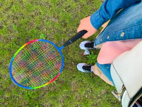 A multi-colored rainbow badminton racket in the hands of a girl on the grass Stock Photos