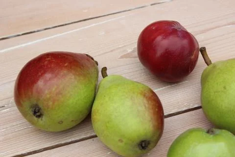 Multi-colored ripe pears and apples on background of boards. Stock Photos